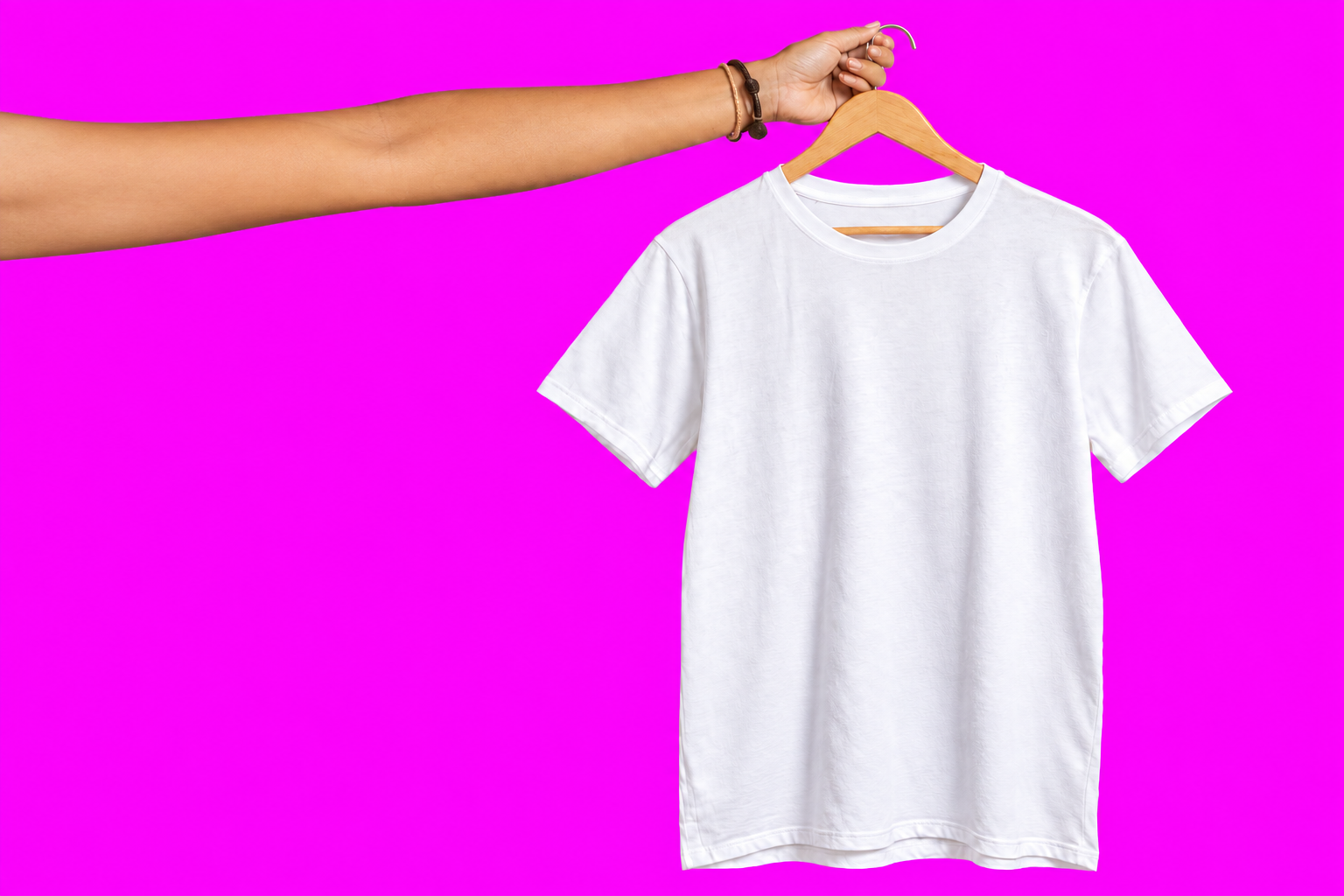 Remera blanca en percha sostenida por una mano desde la izquierda