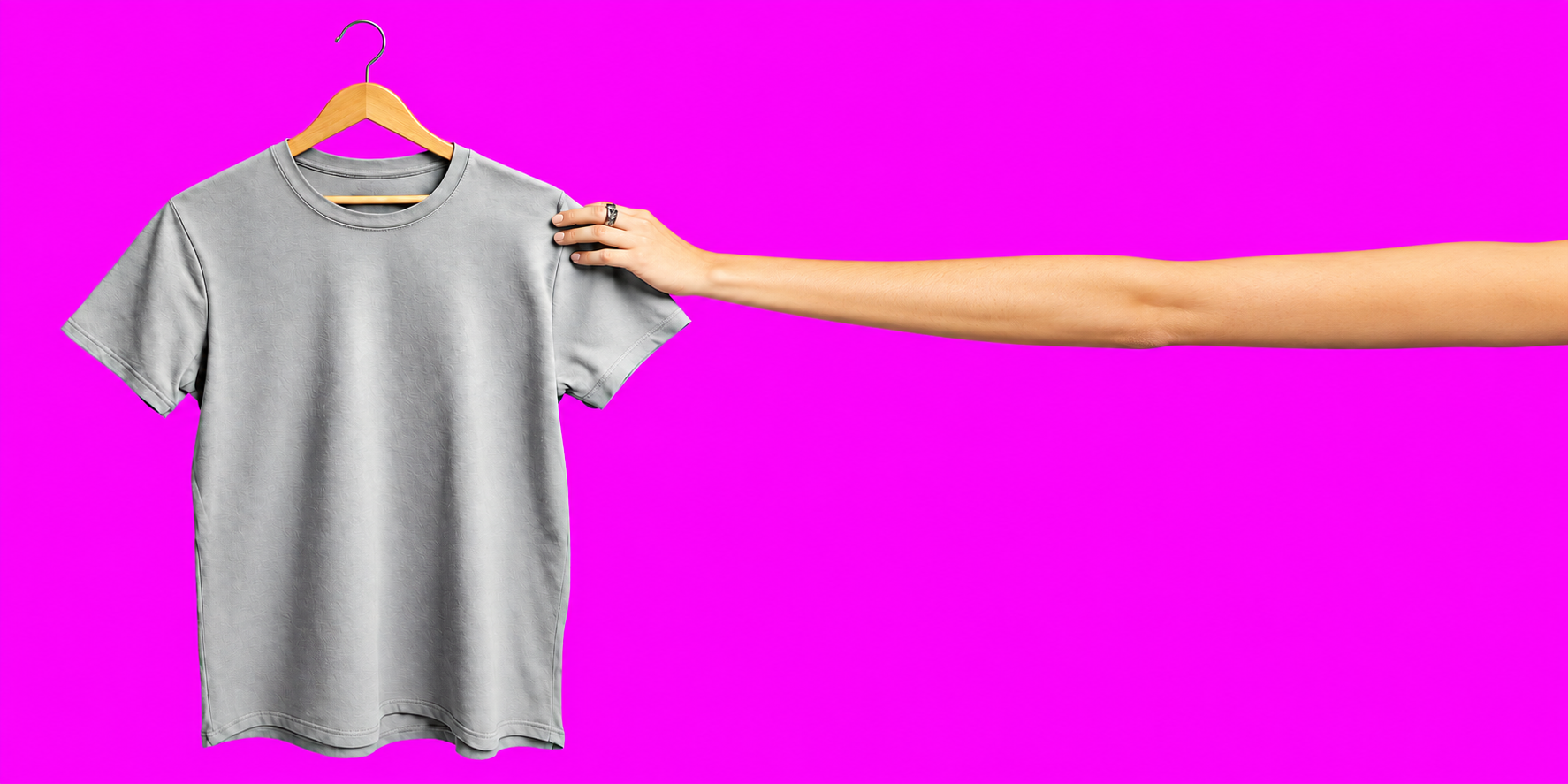 Remera gris sostenida por una mano, delante de las otras prendas