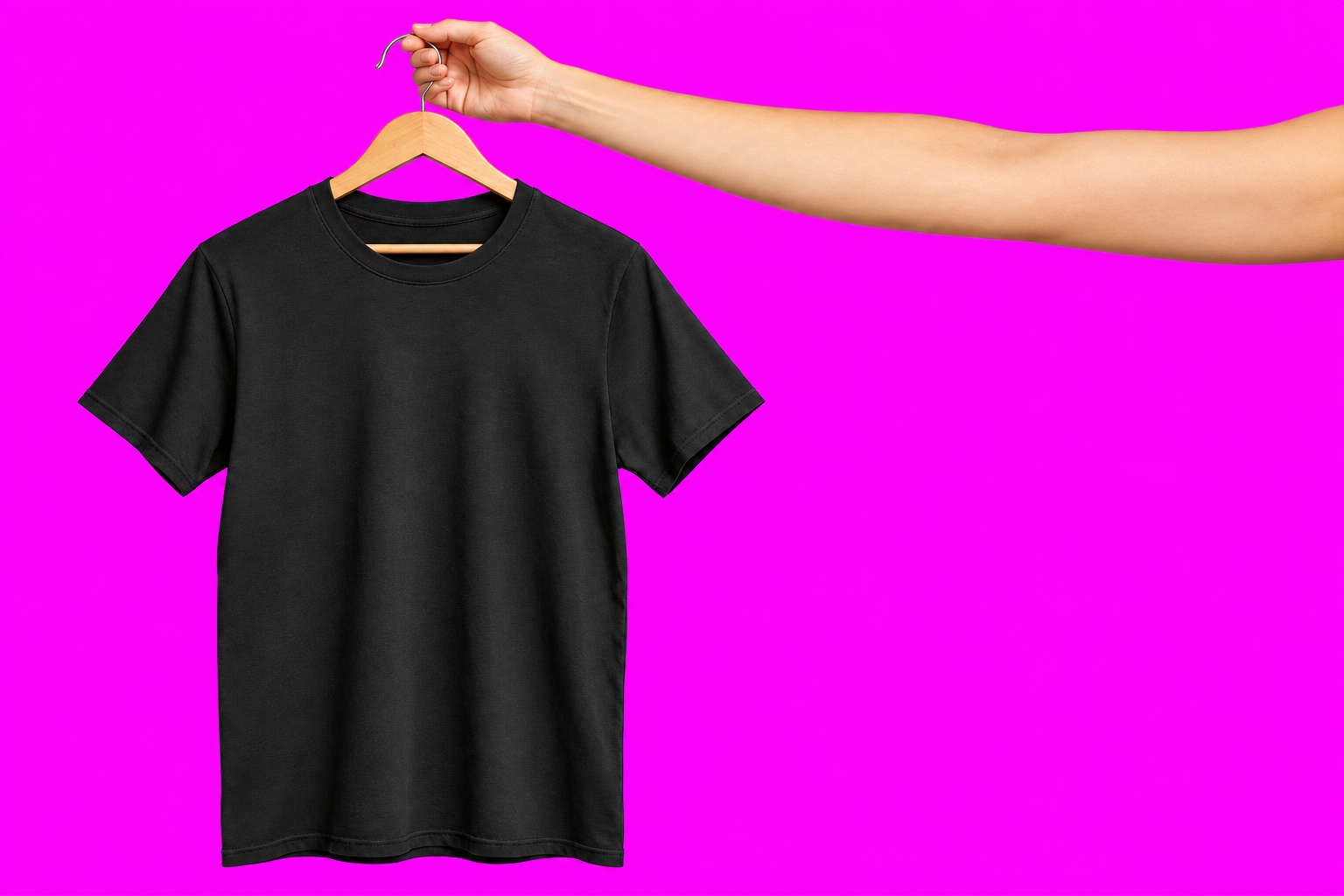 Remera negra en percha sostenida por una mano desde la derecha